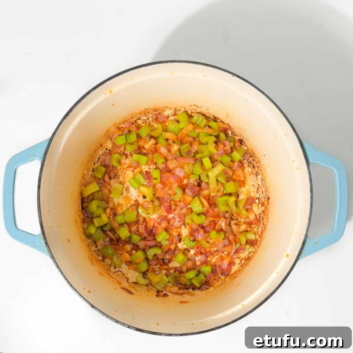Cooking the diced onions and celery in the remaining flavorful oil, softening them for the Jambalaya base.
