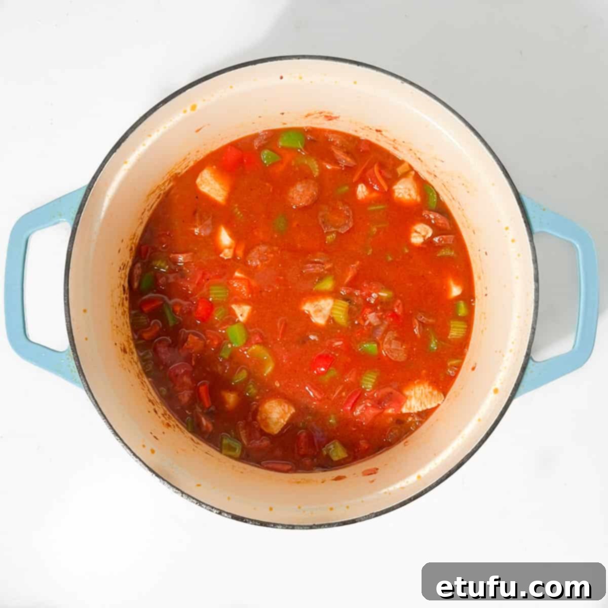Mixing all the ingredients for the jambalaya thoroughly before the lid is placed on for simmering.