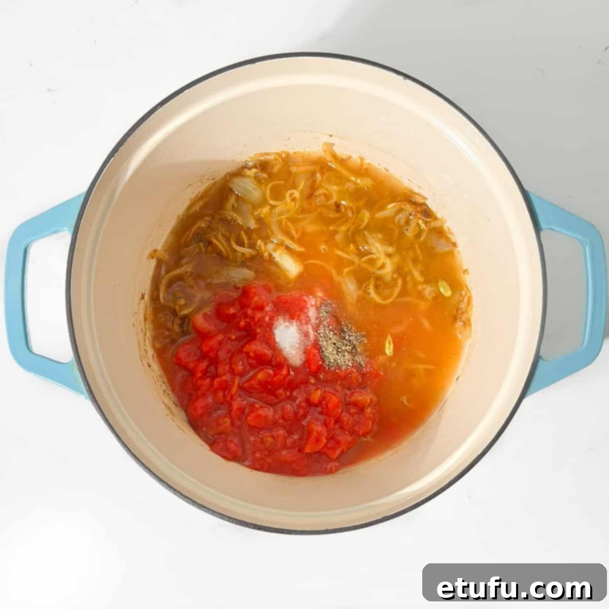 Adding the tomatoes and the chicken stock to the onions.