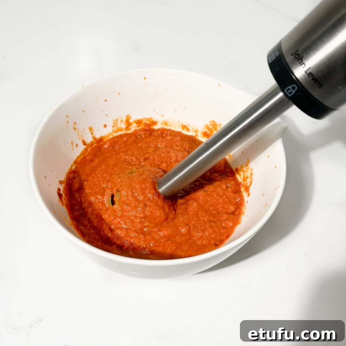 Blitzing the sauce with a stick blender.