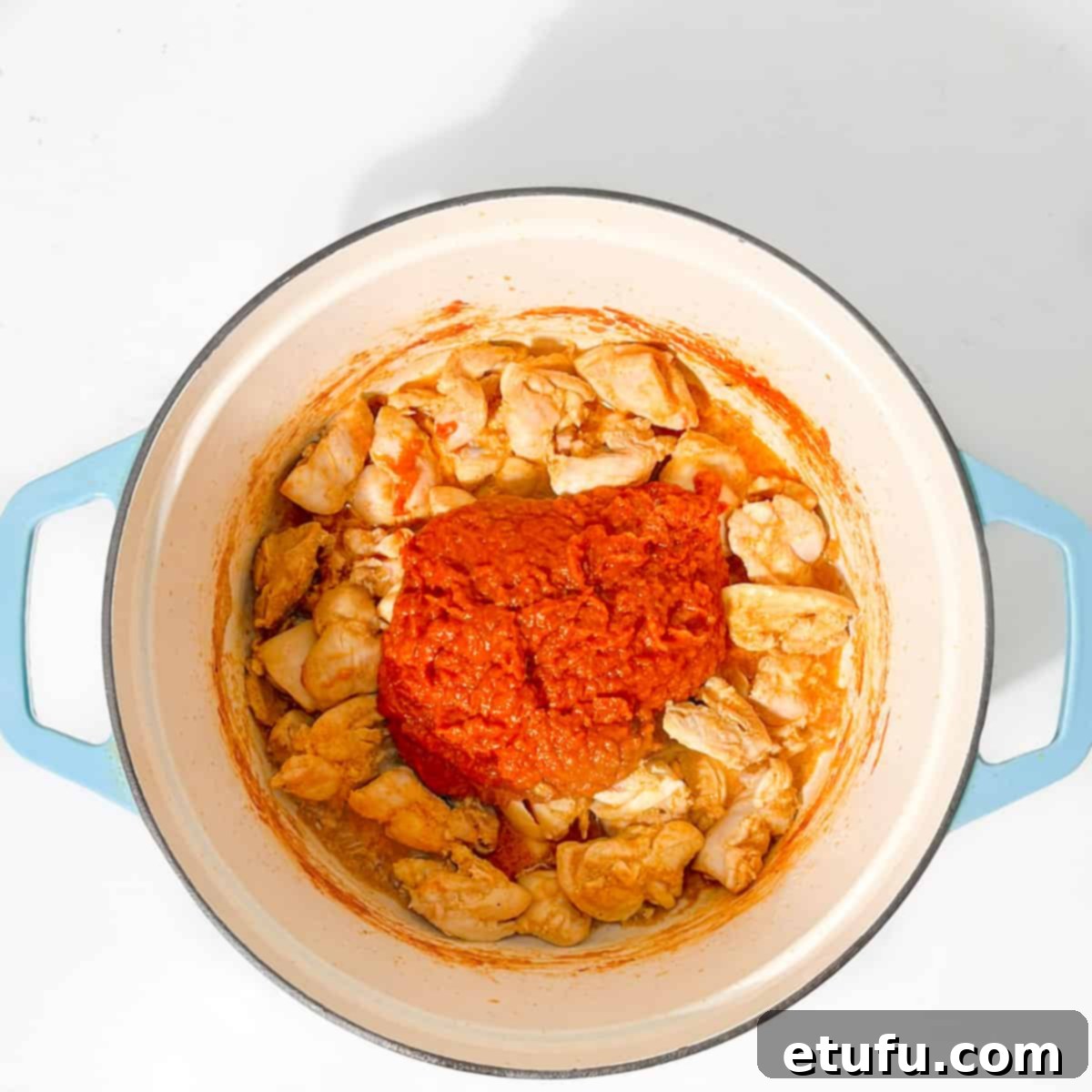 Adding the curry sauce to the chicken in the pan.