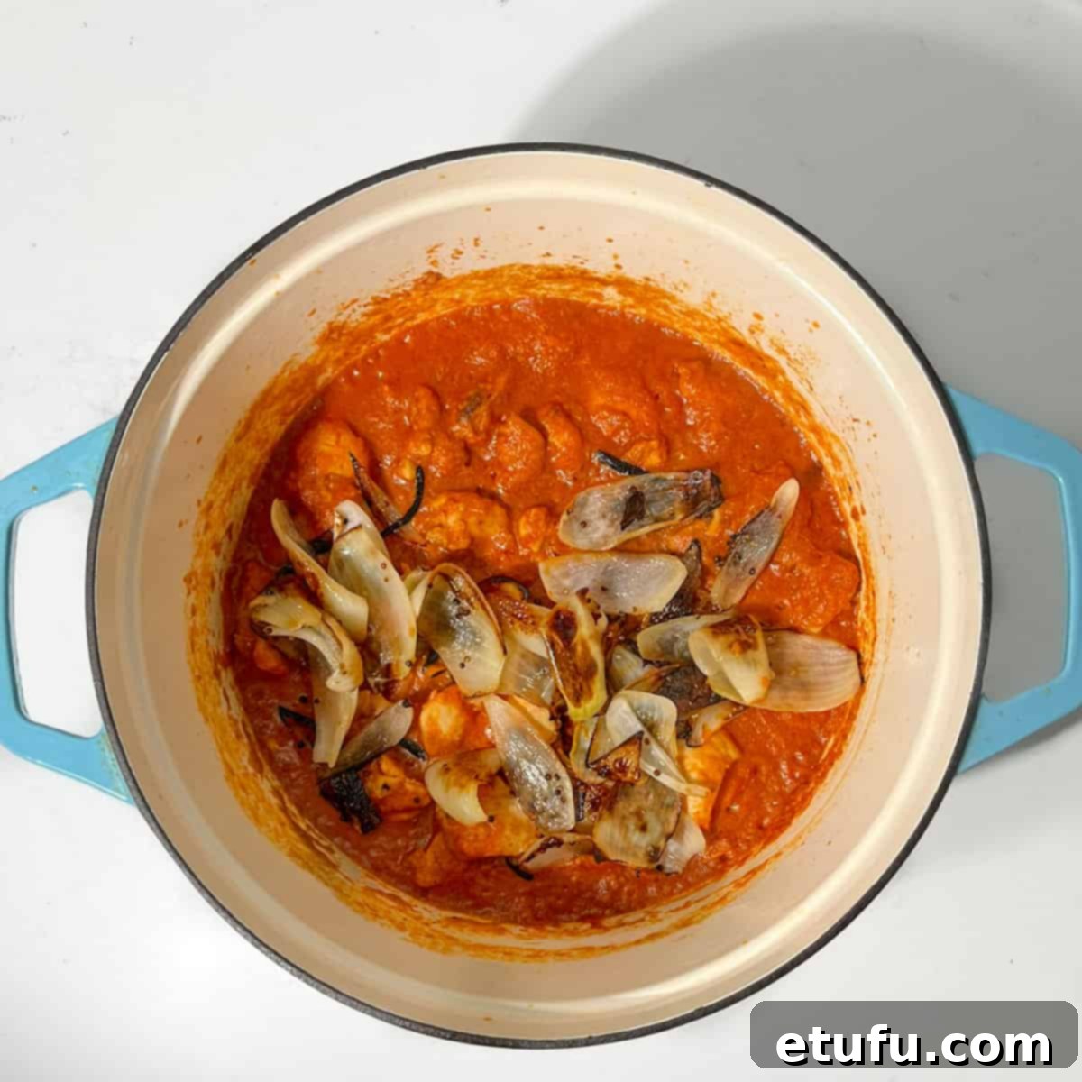 Adding the charred onion petals to the chicken dopiaza.