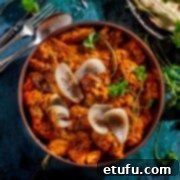 Chicken dopiaza in a copper pan with a plate of flatbreads and a small plate of rice.