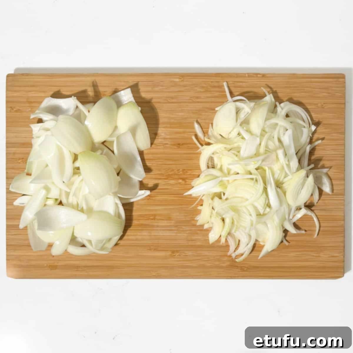 Sliced onions and onion petals in a large wooden chopping board.