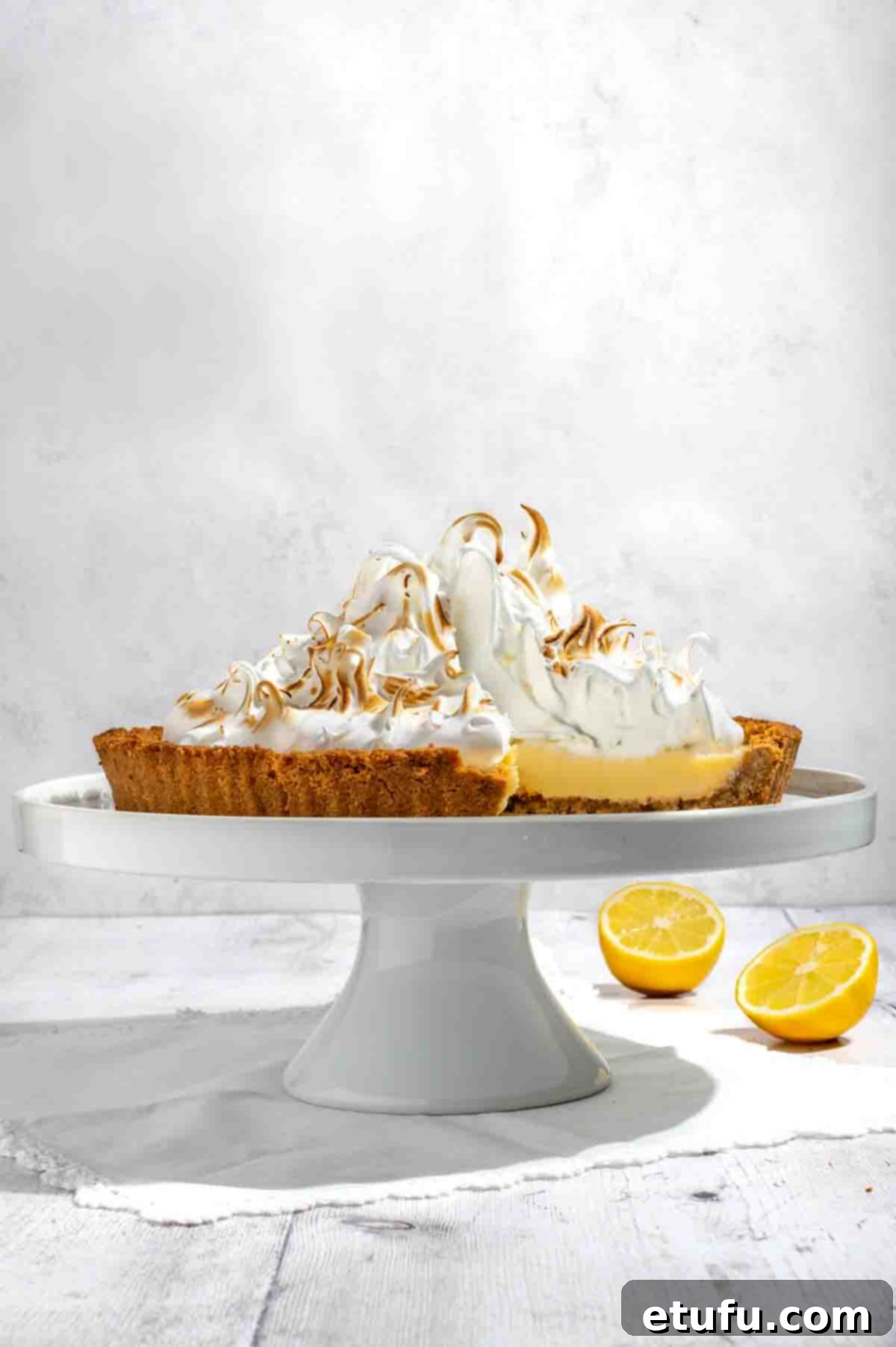 A beautifully presented biscuit base lemon meringue pie on an elegant cake stand, ready to be served.