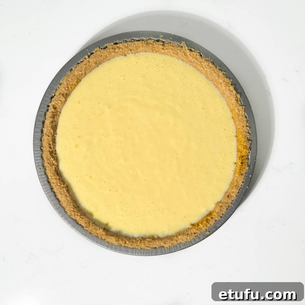 The lemon meringue pie, with its filling set in the biscuit base, cooling on a wire rack.