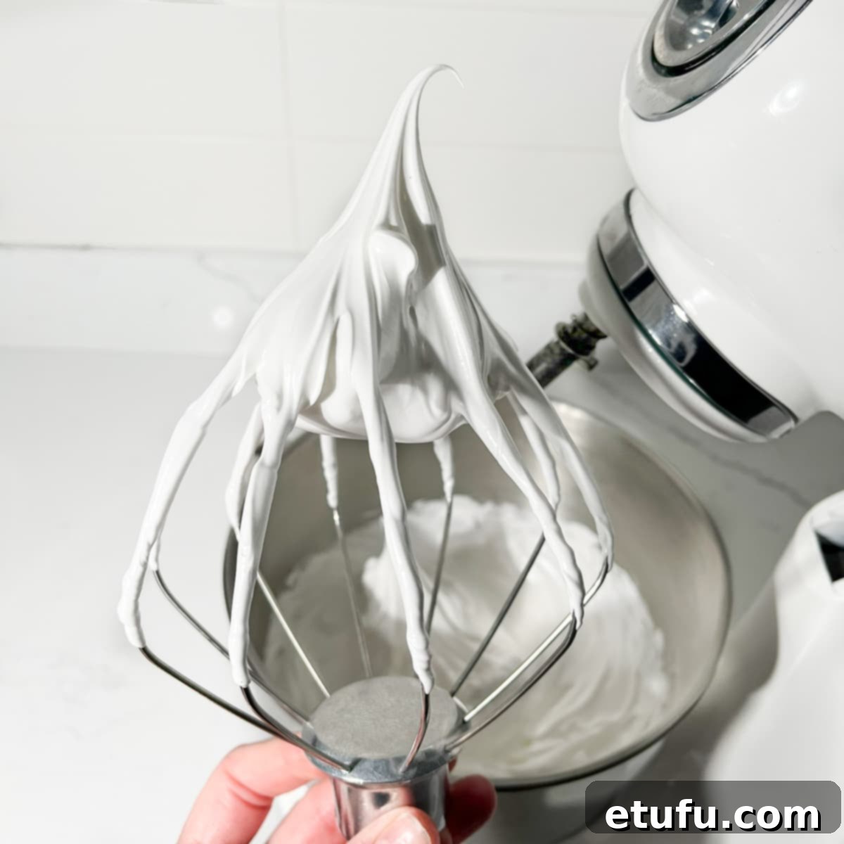 A close-up of perfectly whipped Swiss meringue showing stiff, glossy peaks.