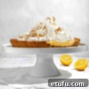 A beautifully presented biscuit base lemon meringue pie on an elegant cake stand.