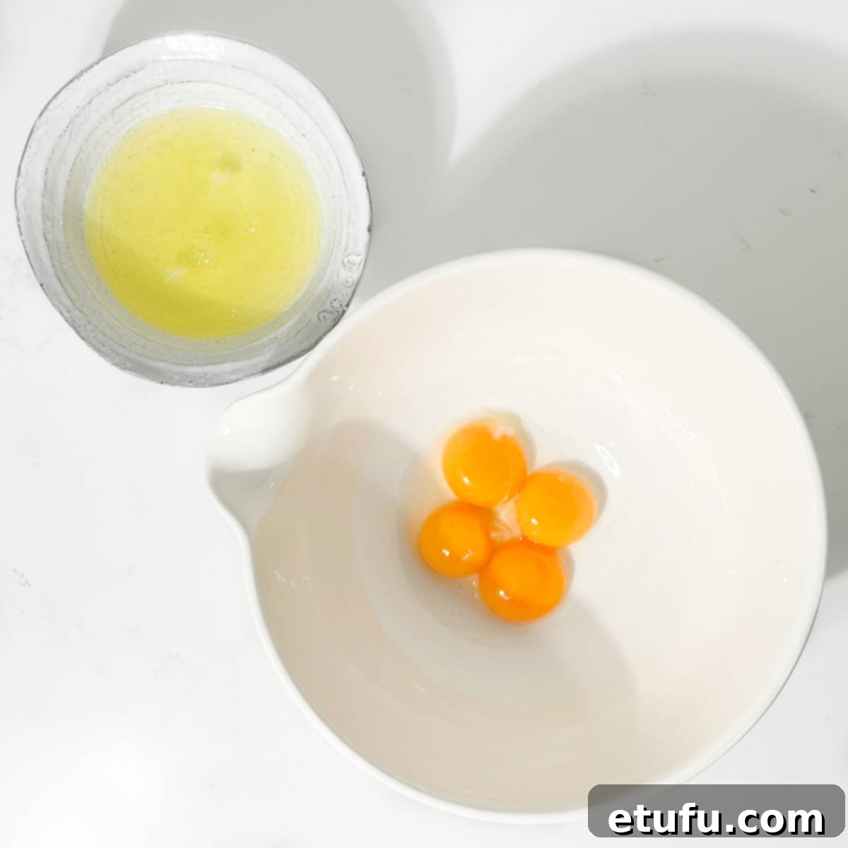 Separated egg yolks and whites in separate bowls, ready for the recipe.