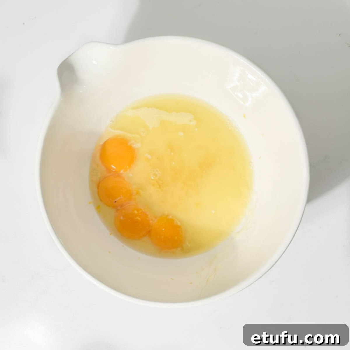 Egg yolks, condensed milk, and fresh lemon juice combined in a large white mixing bowl.