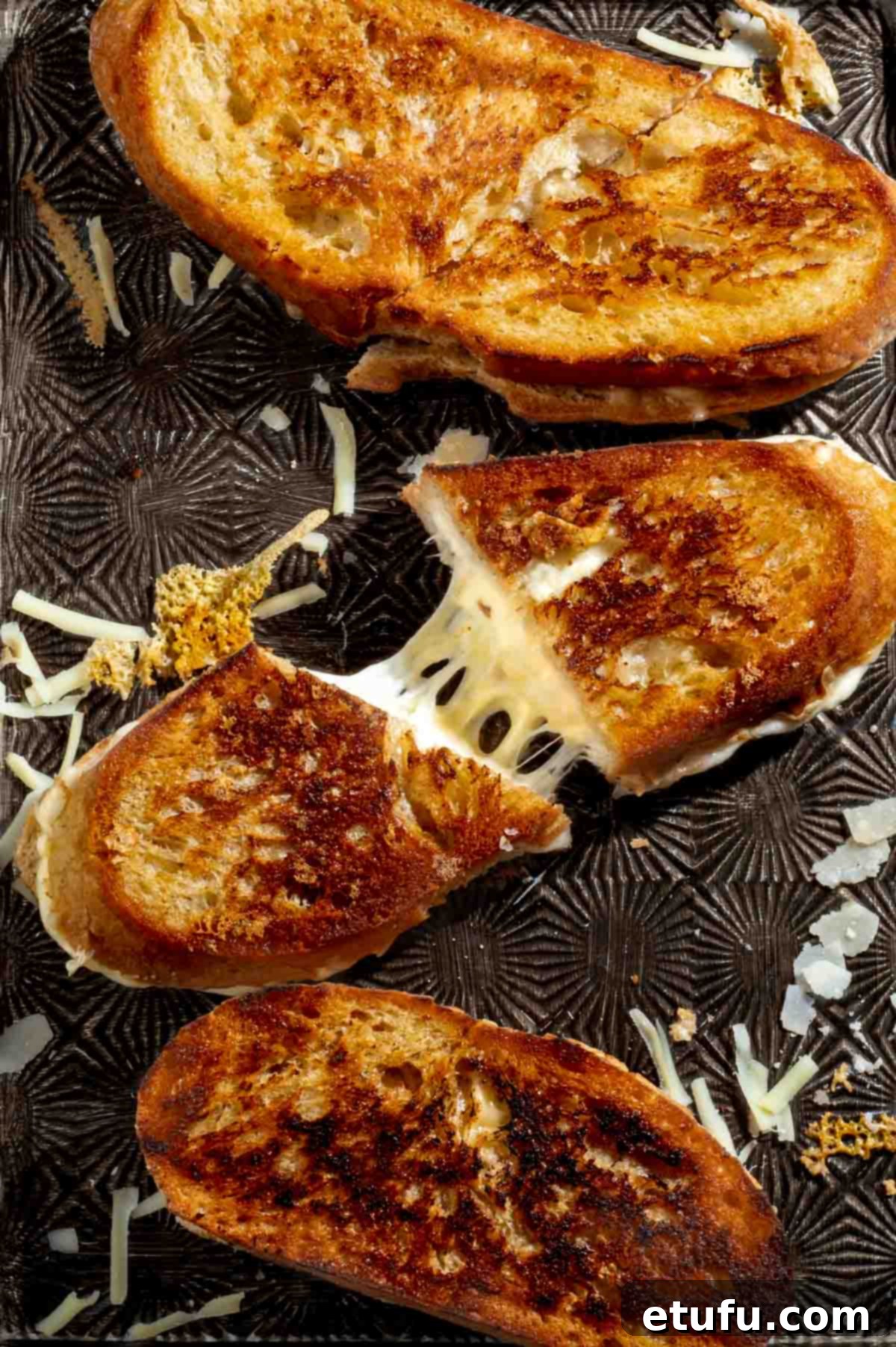 Sourdough grilled cheese sandwich sliced and pulled apart to show melted cheese inside.