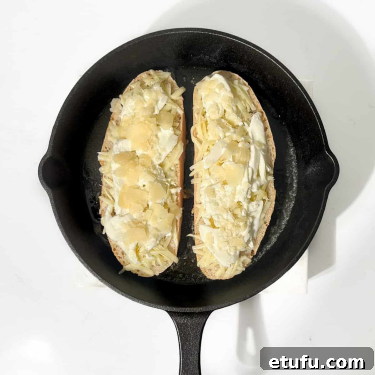 Grilling two slices of sourdough bread topped with cheese in a cast irons pan.