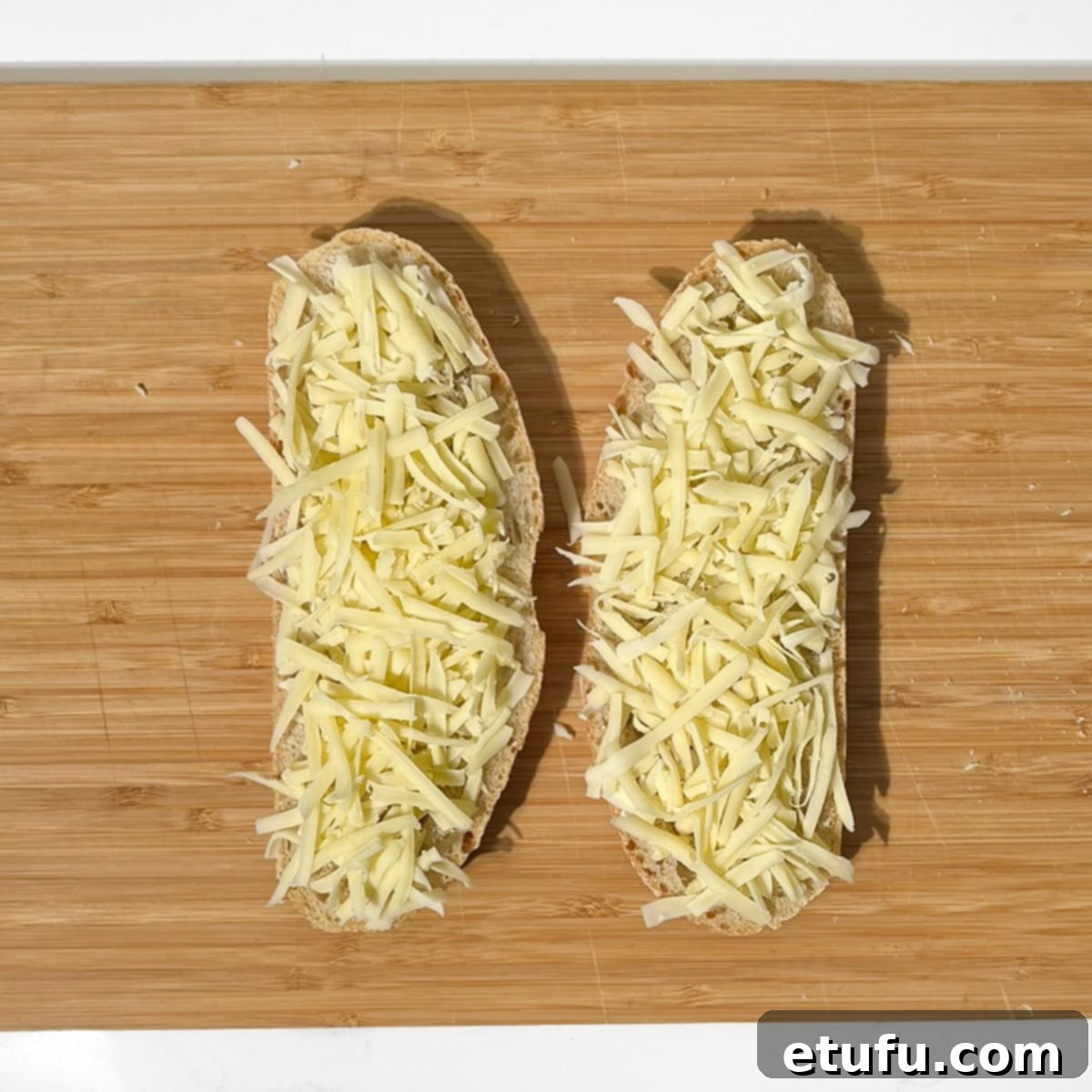 Two slices of bread topped with grated Emmental cheese.