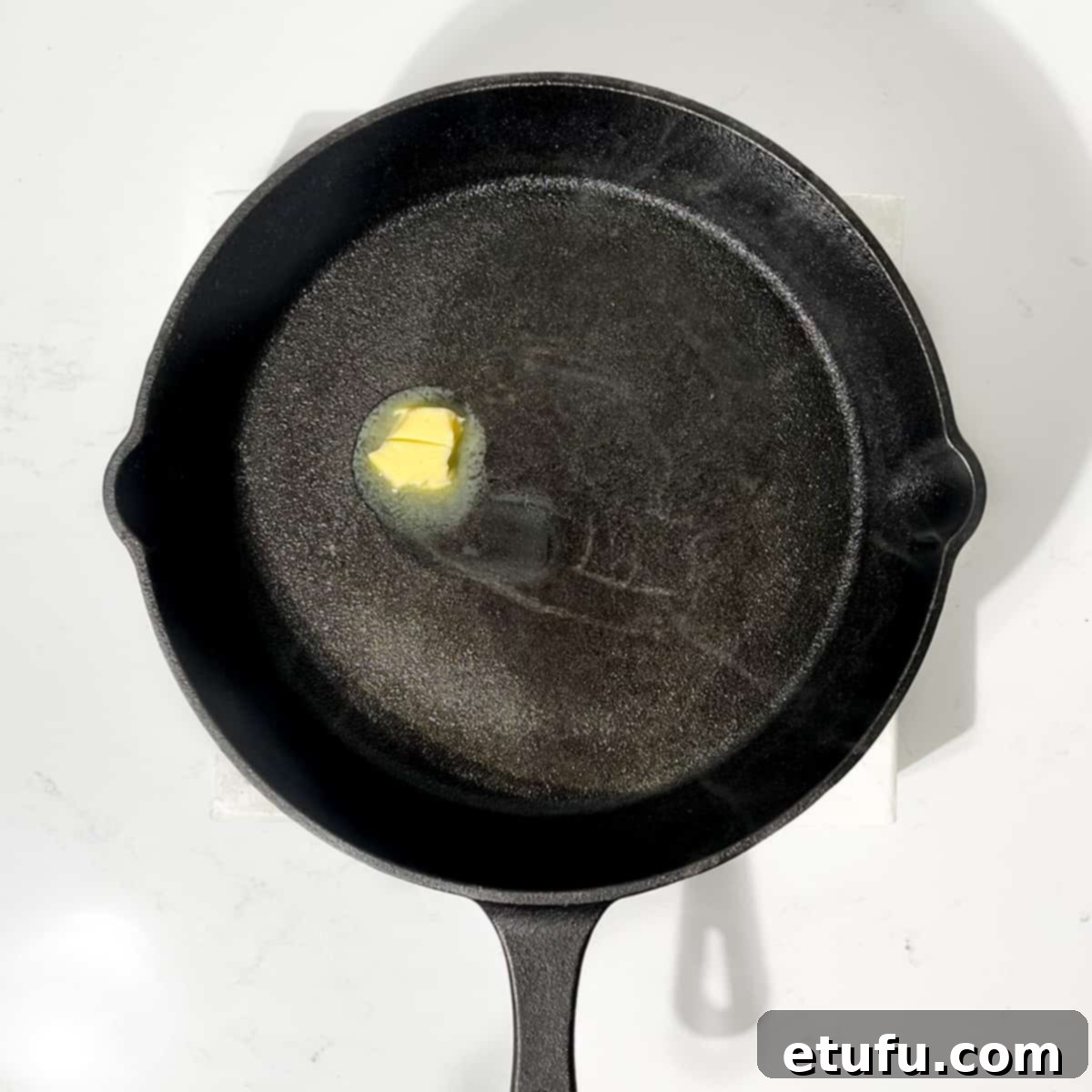 Melting a small knob of butter in a cast iron skillet.