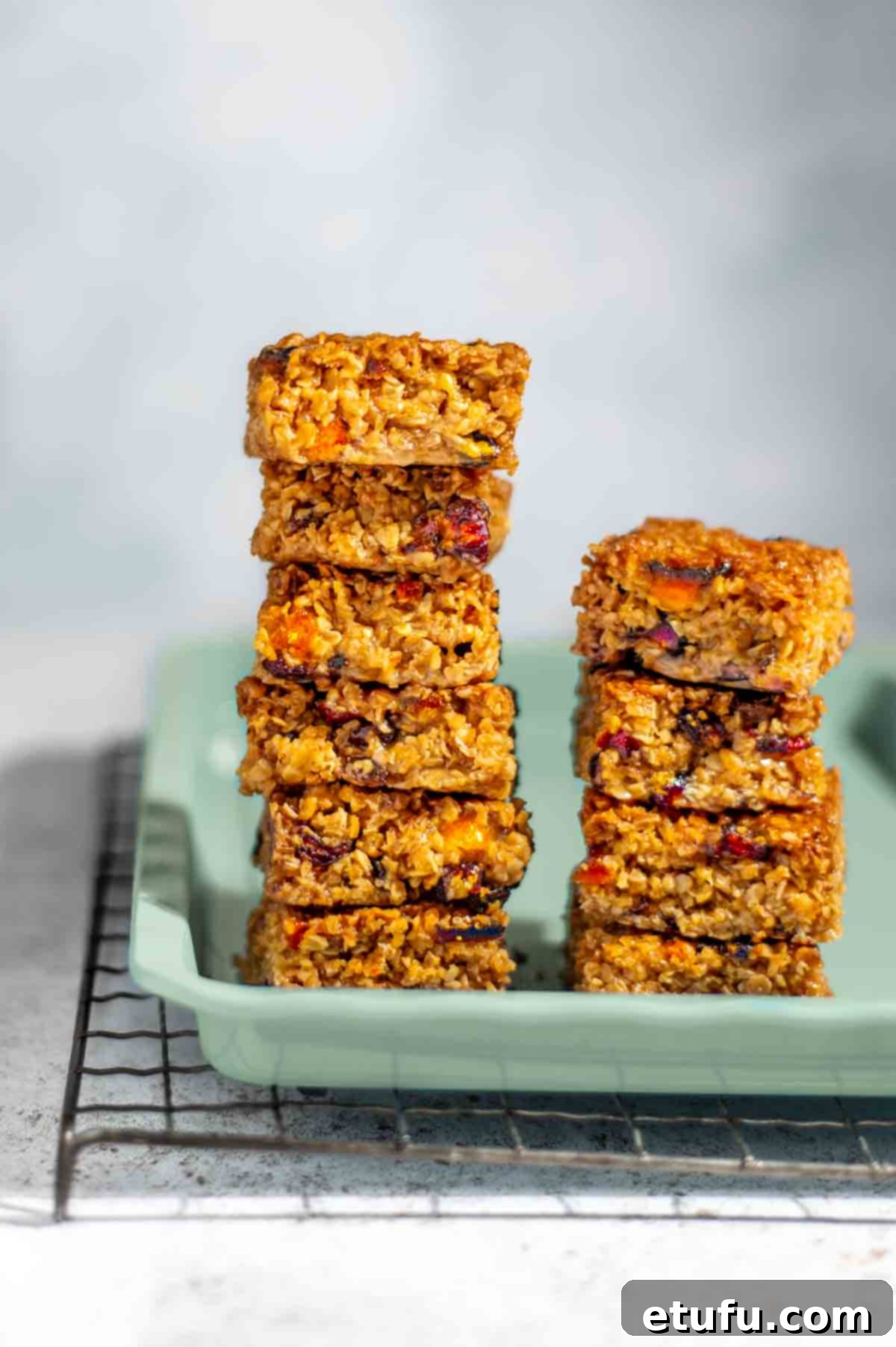 Two stacks of fruity flapjacks on a green baking tray.