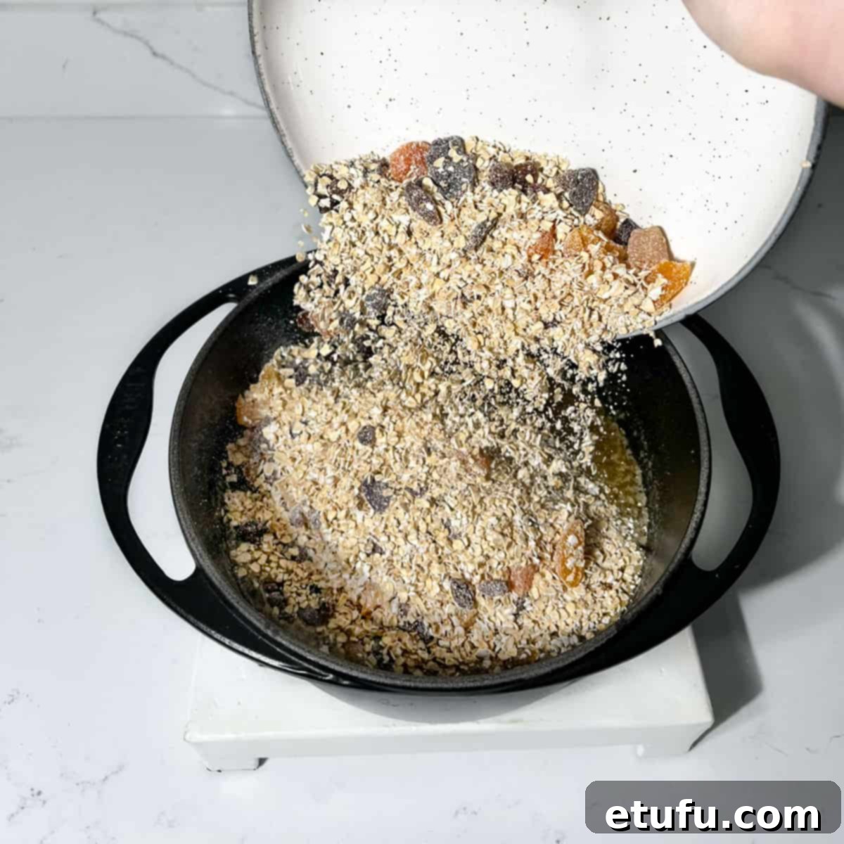Adding the oats and dried fruit to the melted ingredients in a large saucepan.