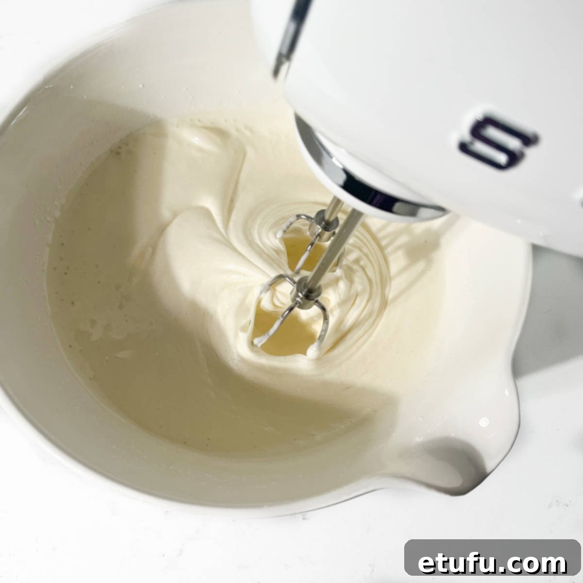 Beating the eggs and sugar mixture until it's light, fluffy, and pale, showing thick trails.