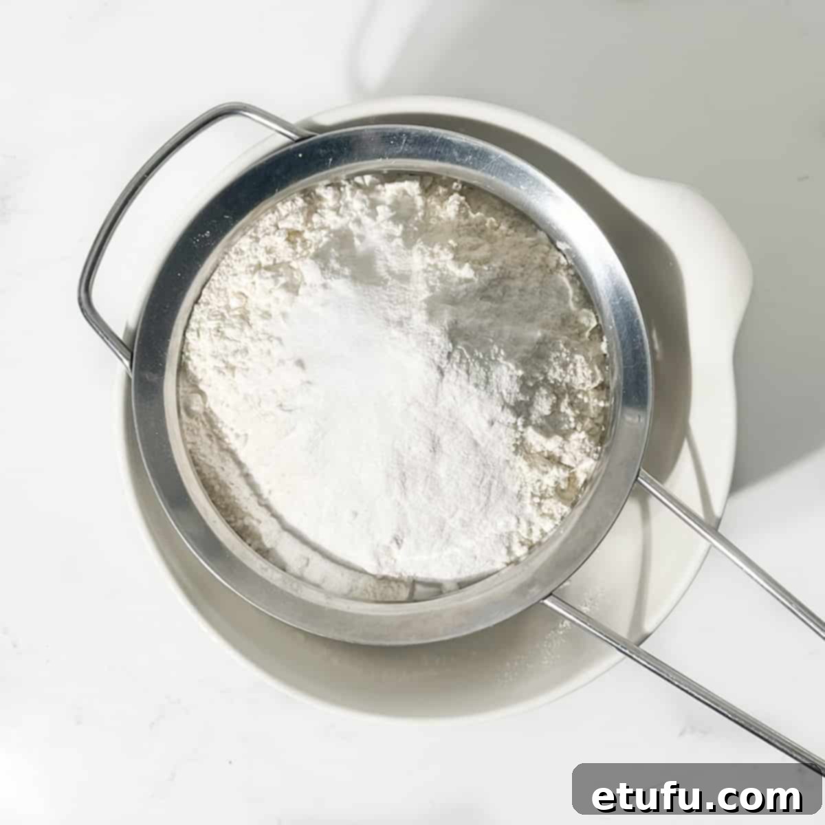 Sifting together all-purpose flour, baking powder, and salt into a large white bowl.