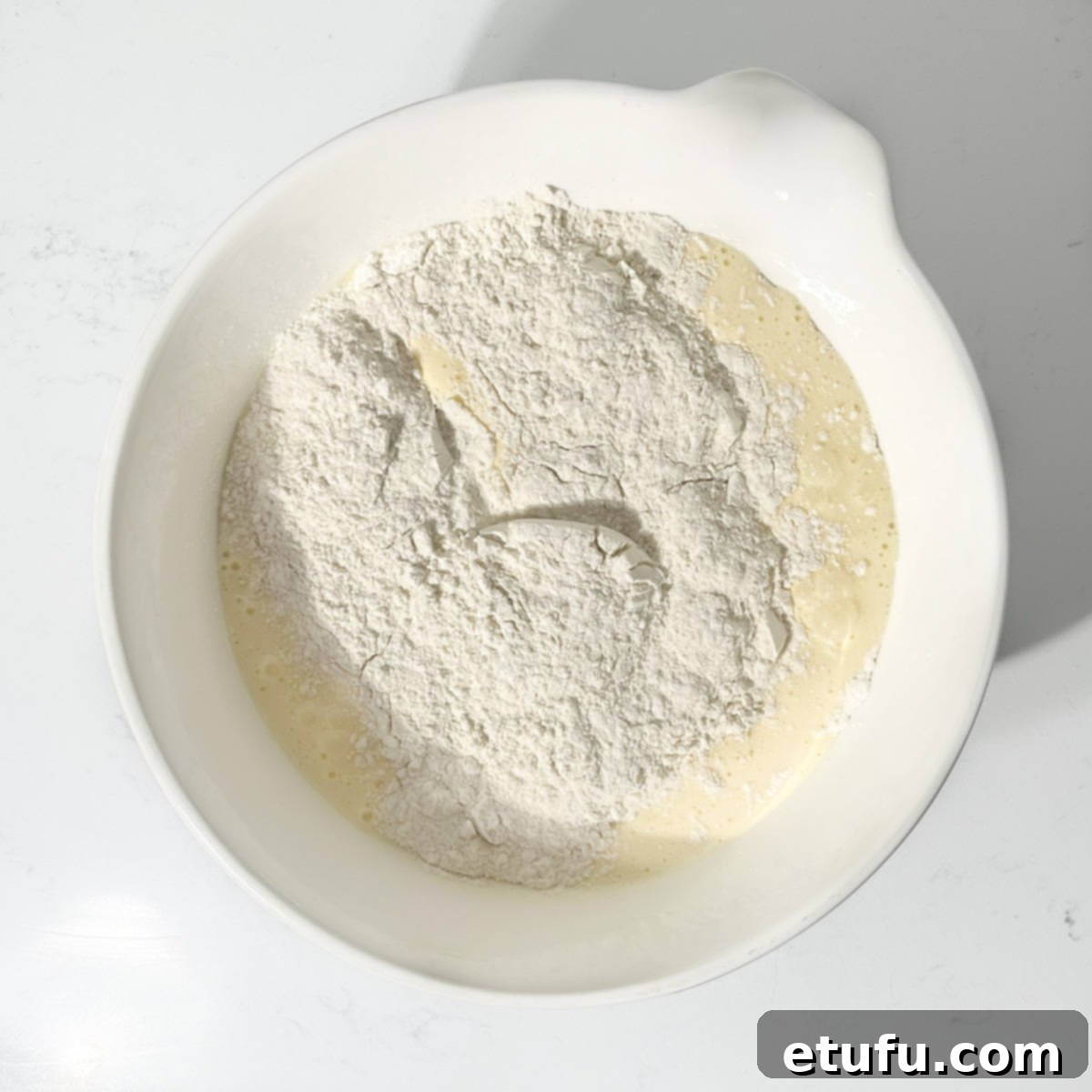 Adding half of the sifted dry ingredients to the beaten egg and sugar mixture.