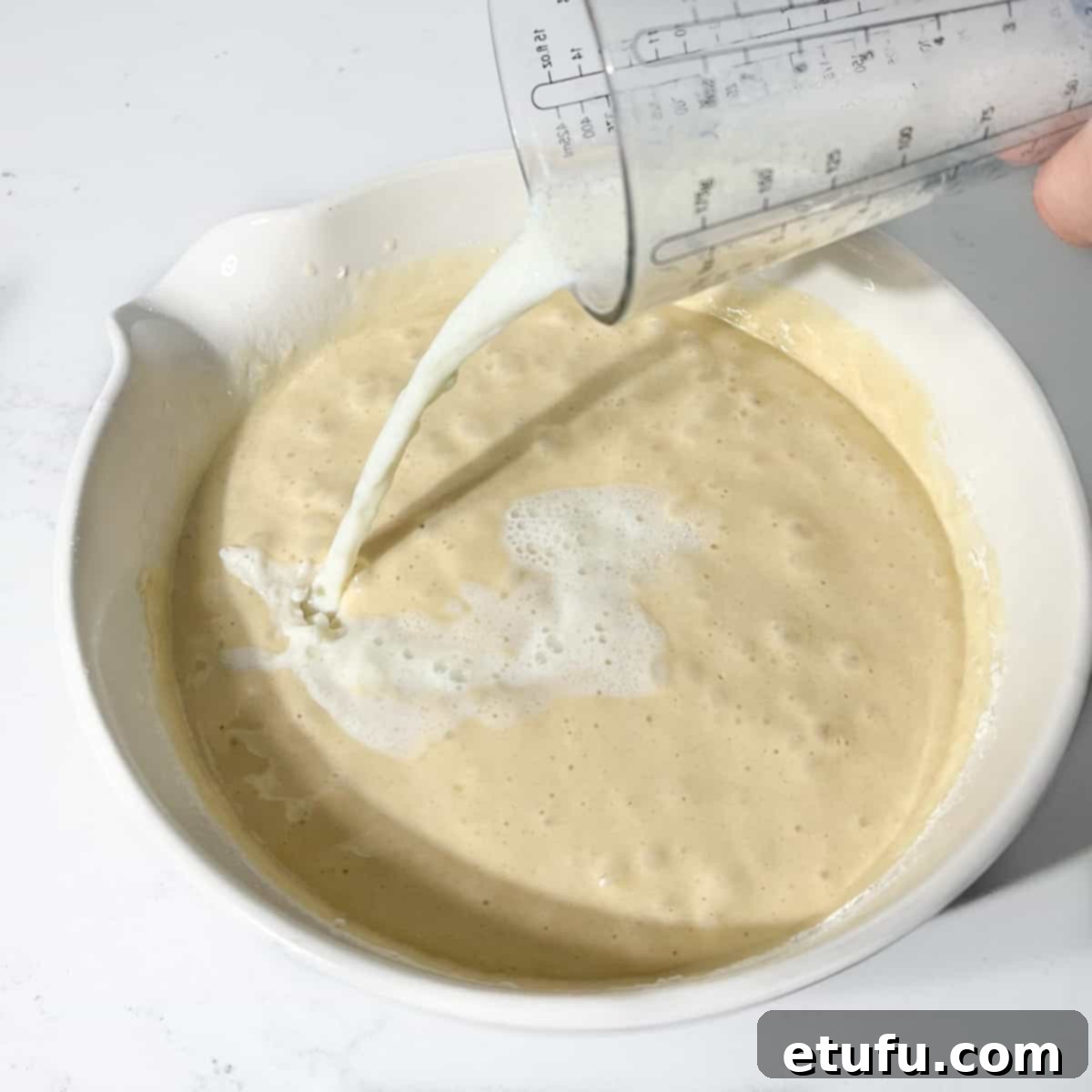 Adding half of the milk and oil mixture to the cake batter.