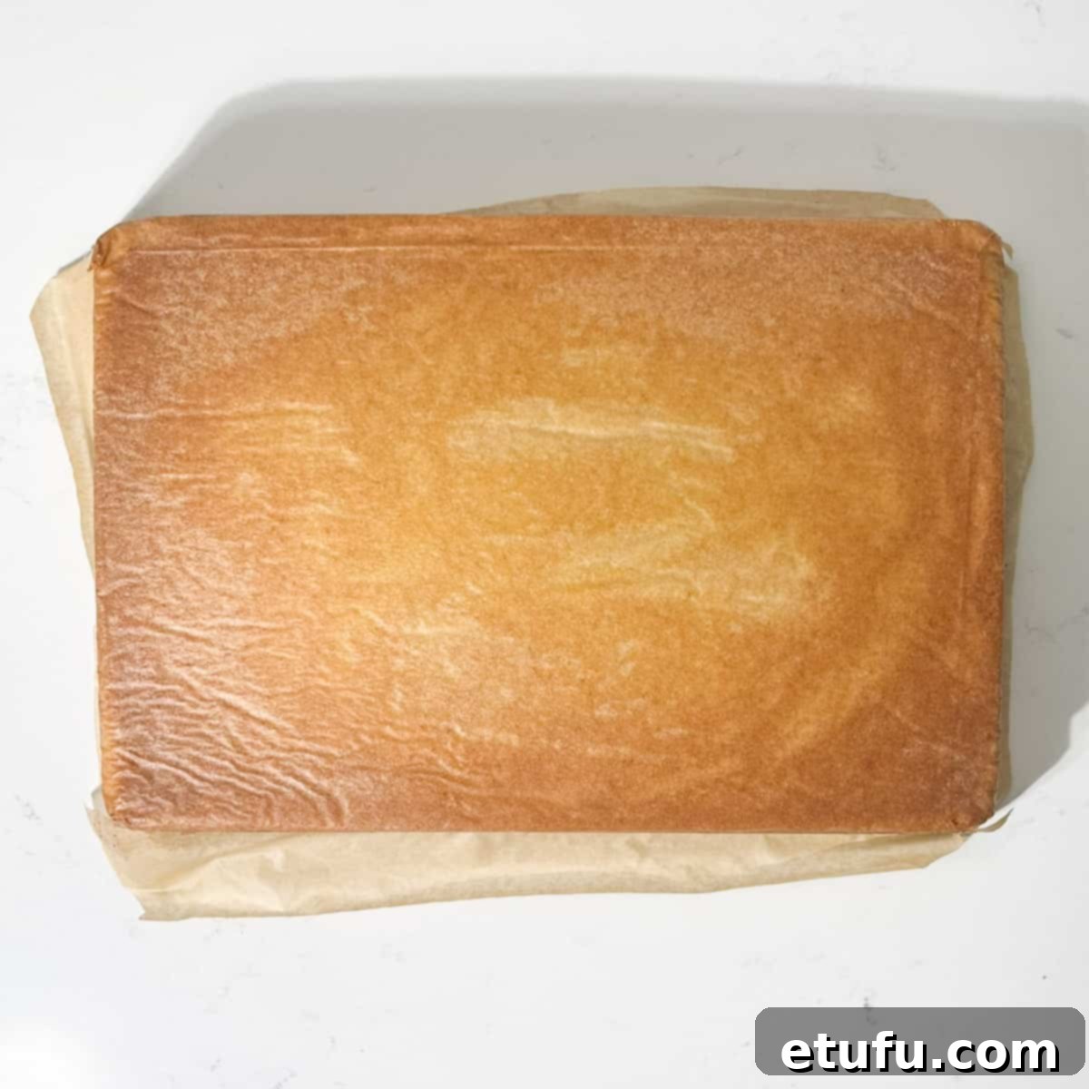 Carefully flipping the baked vanilla tray bake upside down onto a wire cooling rack.