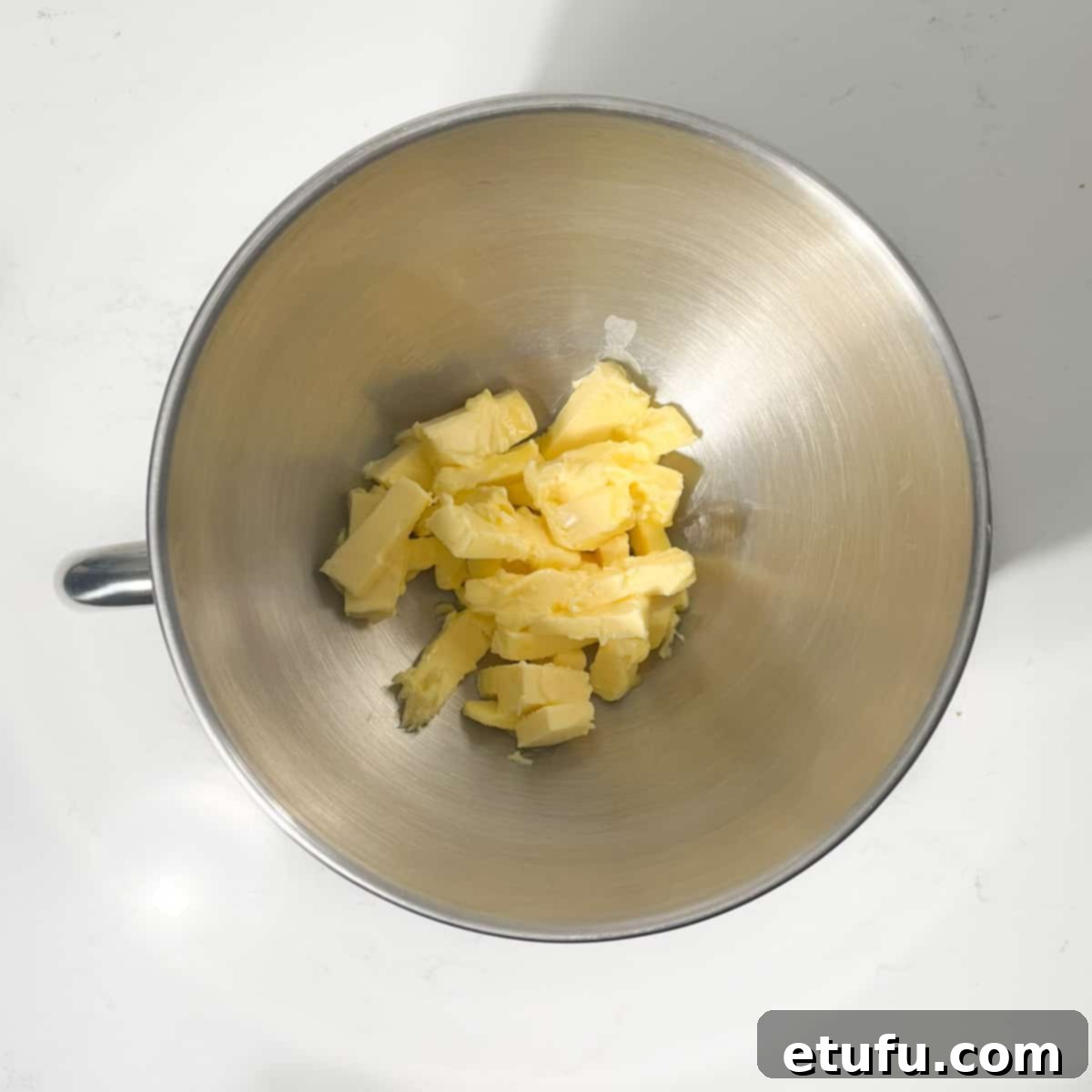 Adding cubed softened butter to the bowl of a stand mixer.
