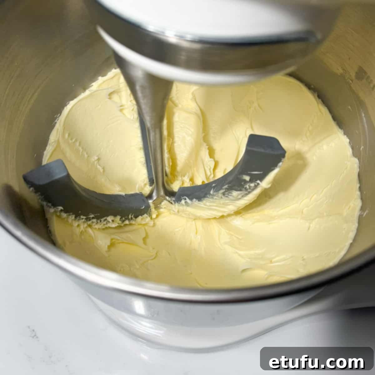 Whipping the butter in a stand mixer until it becomes light, soft, and fluffy.