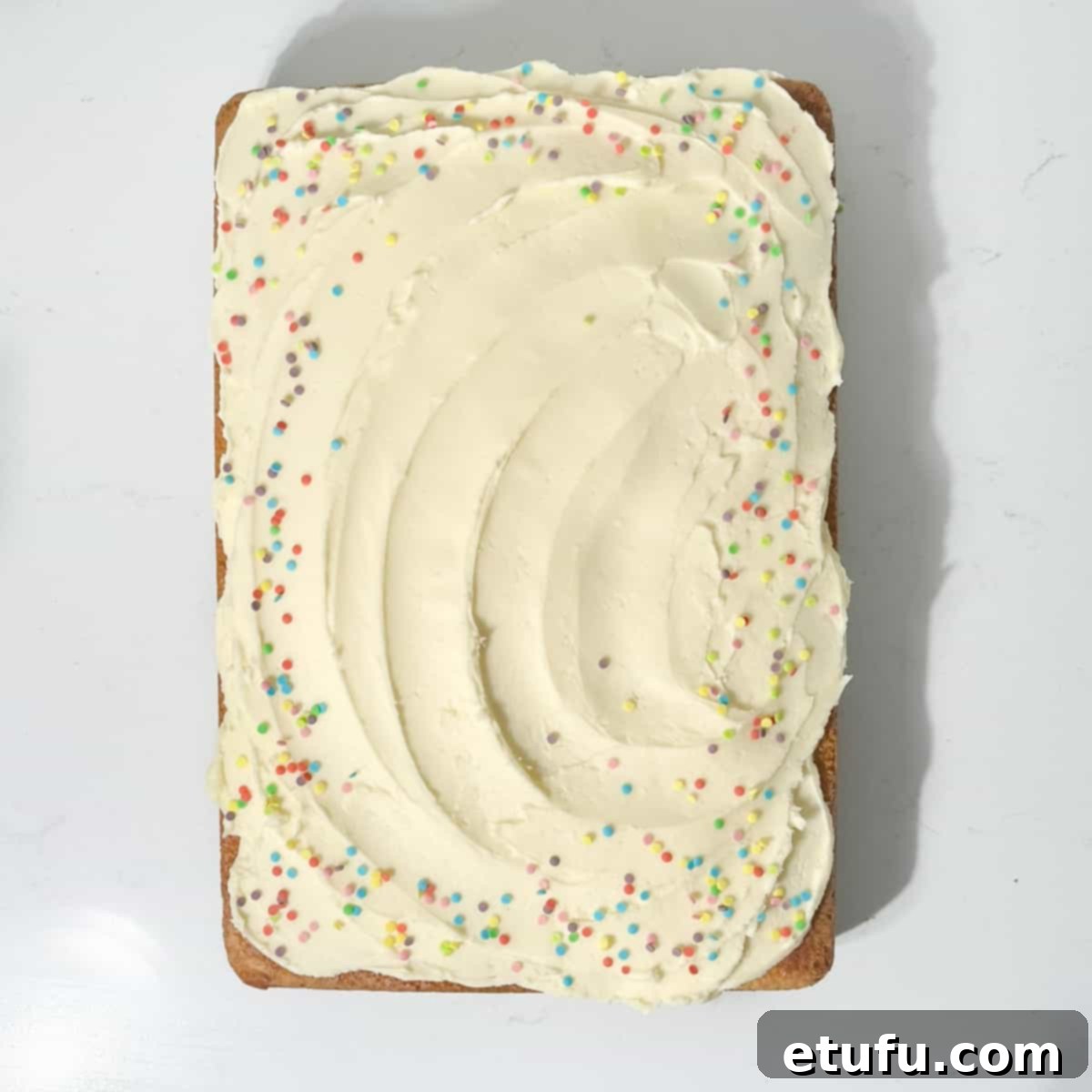 A completed vanilla tray bake lavishly topped with creamy icing and vibrant sprinkles.