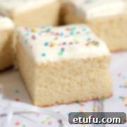 One slice of vanilla tray bake with sprinkles, featuring a moist crumb and creamy frosting.