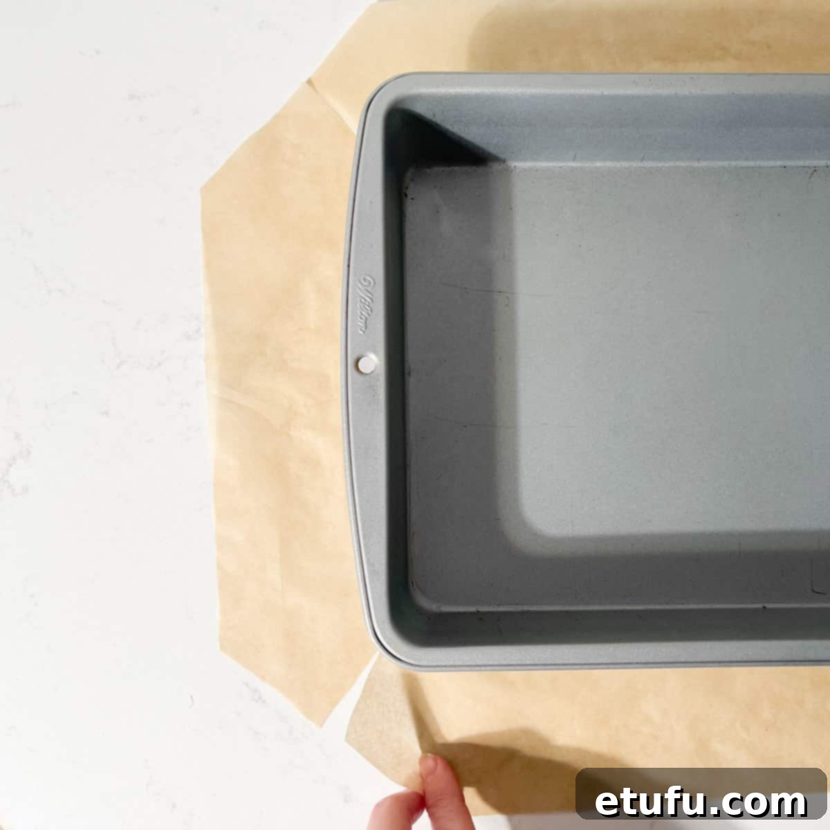 Baking paper with diagonal slits cut into each corner to fit into the tin.