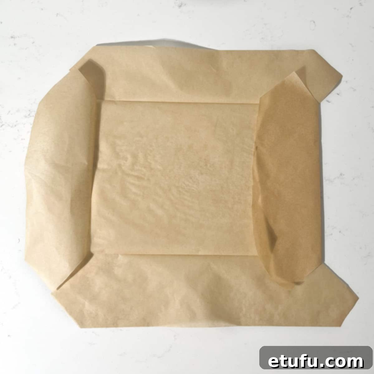 A piece of baking paper being folded along the seams before placing it in the baking tin.