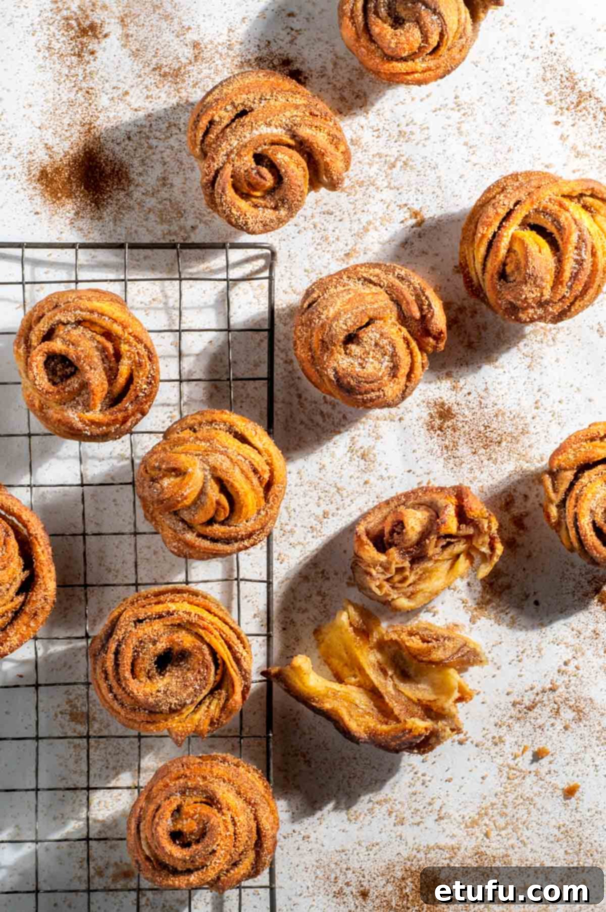 Cruffins scattered on a white background sprinkled with cinnamon sugar.