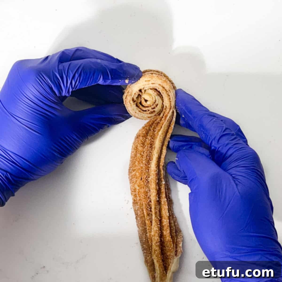 Rolling croissant dough into a cruffin shape.