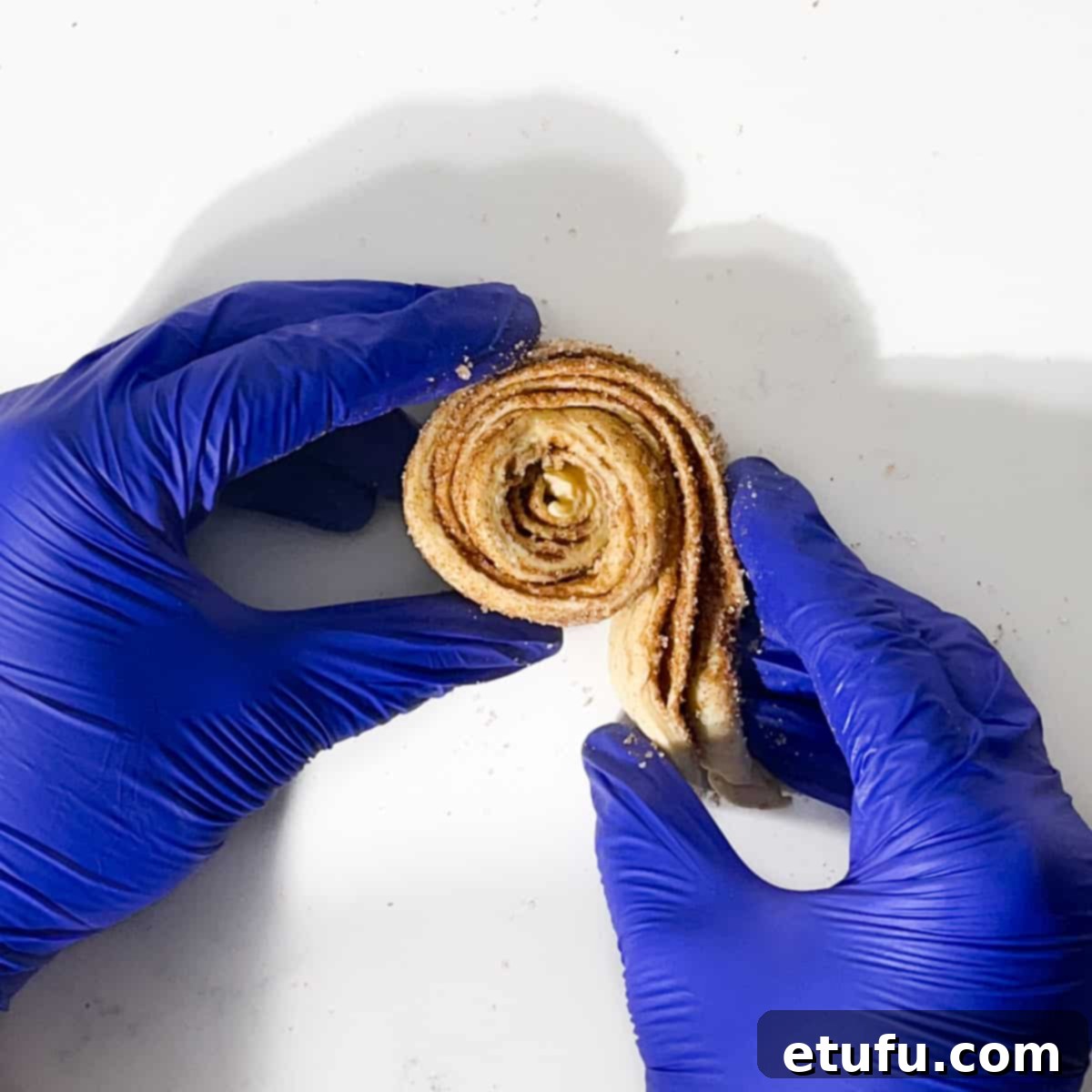 Rolling croissant dough into a cruffin shape.