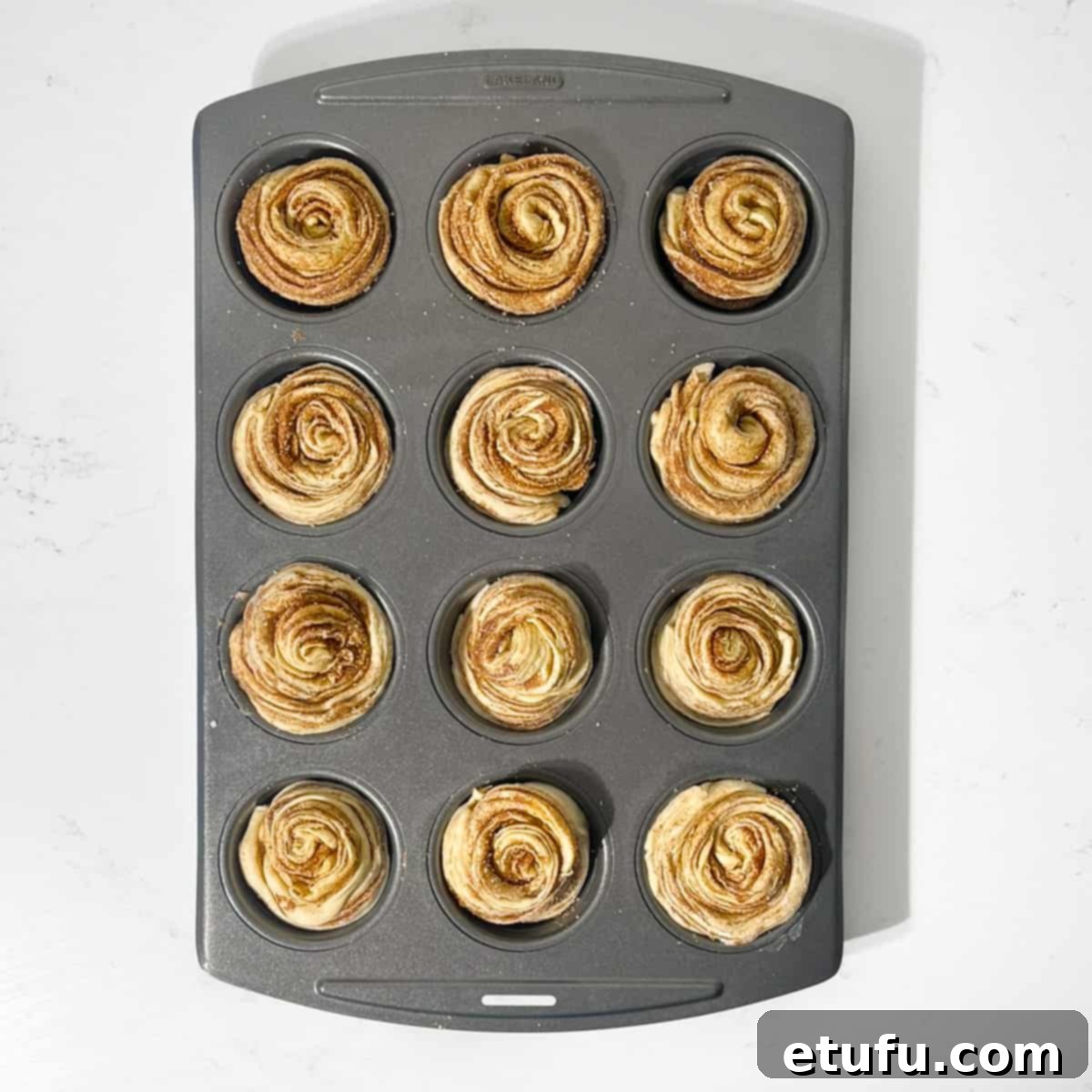 Rolled up cruffins in a muffin tin, ready for the oven.