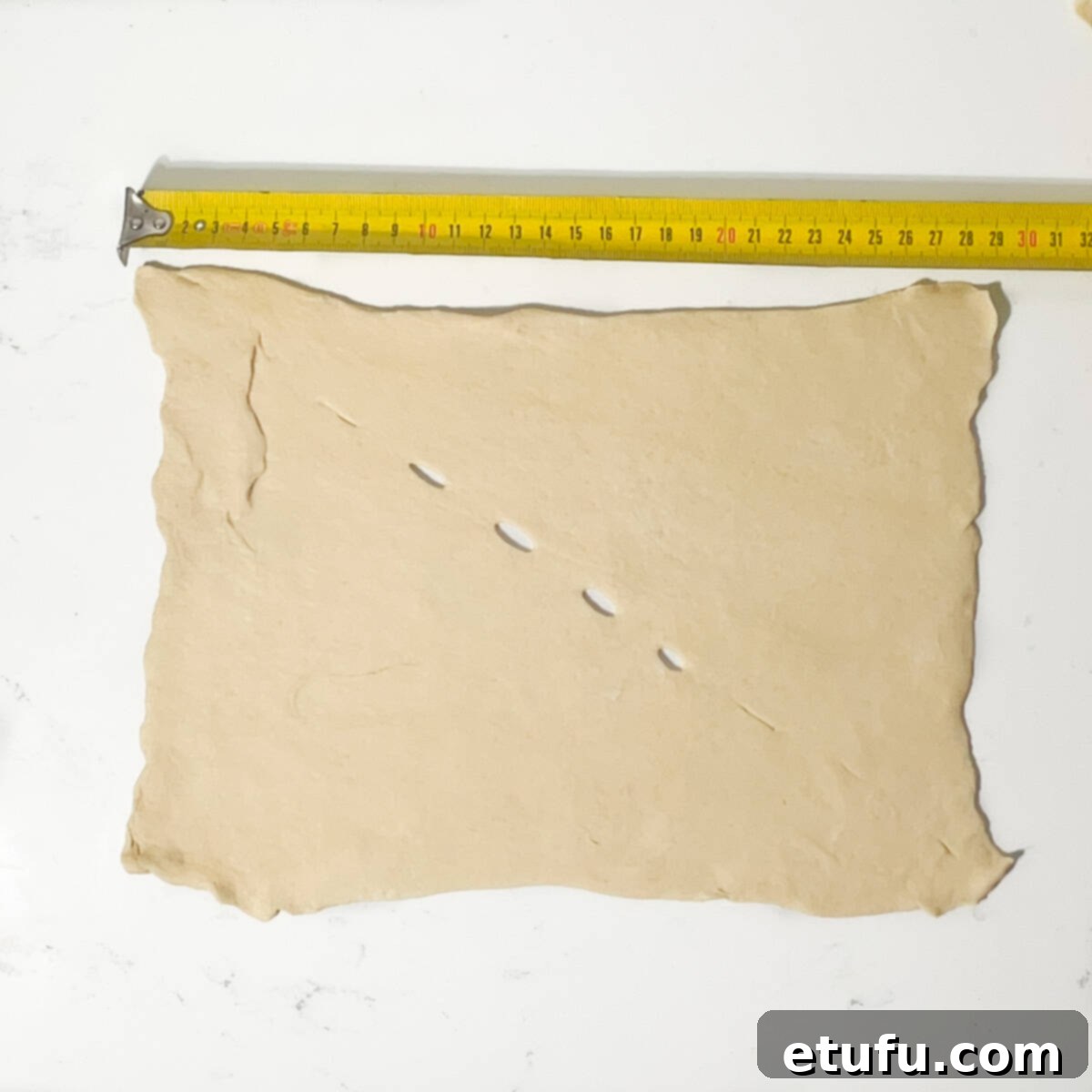 Showing the measurement of the dough square with a measuring tape.