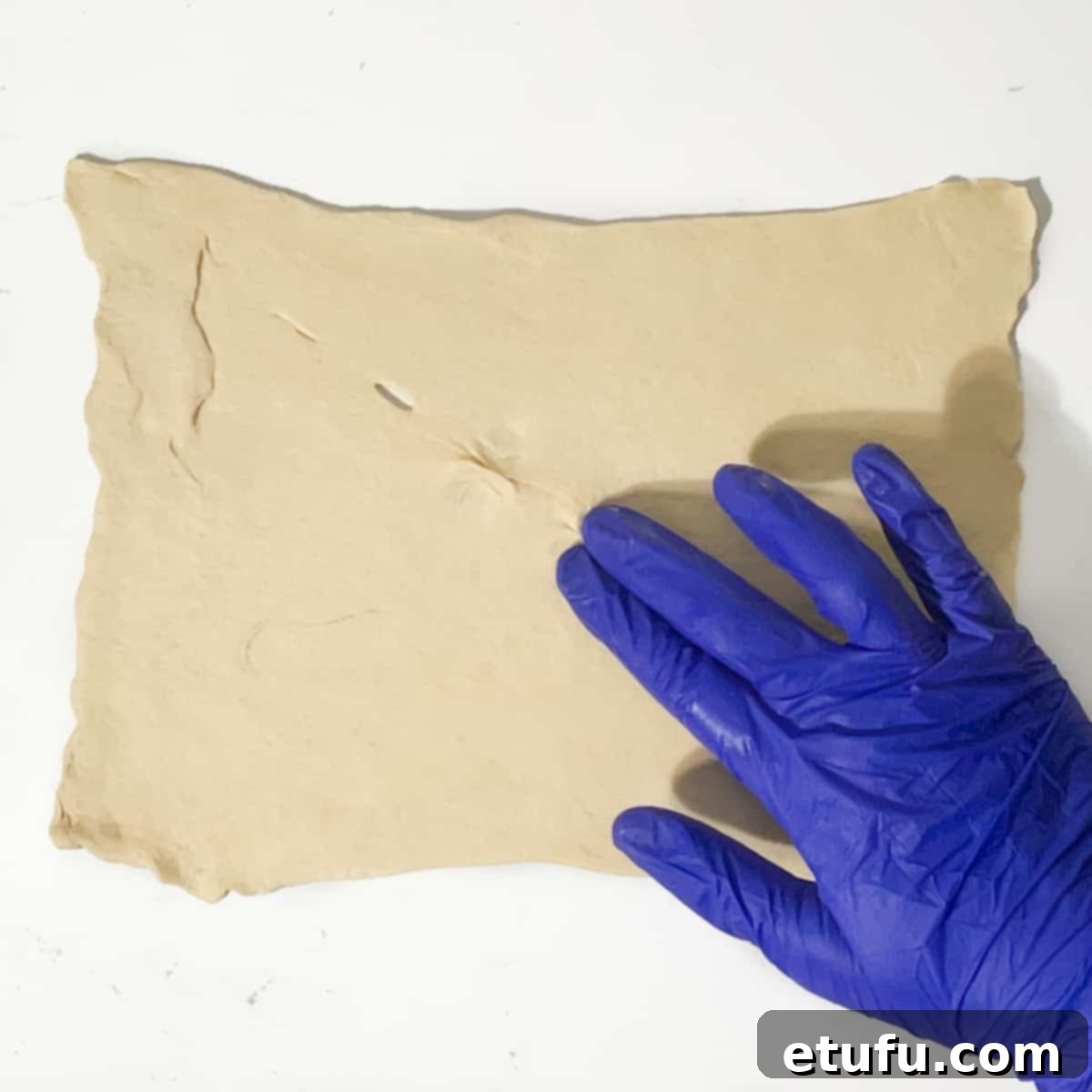 Pinching the perforated holes in the dough shut with fingertips.