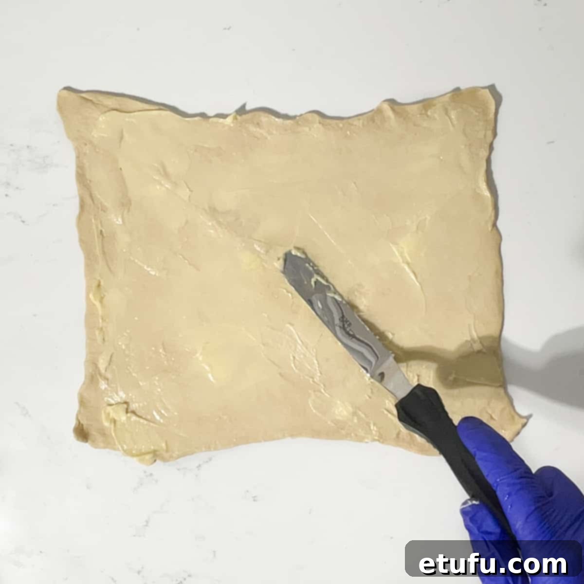 Spreading butter onto the croissant dough.