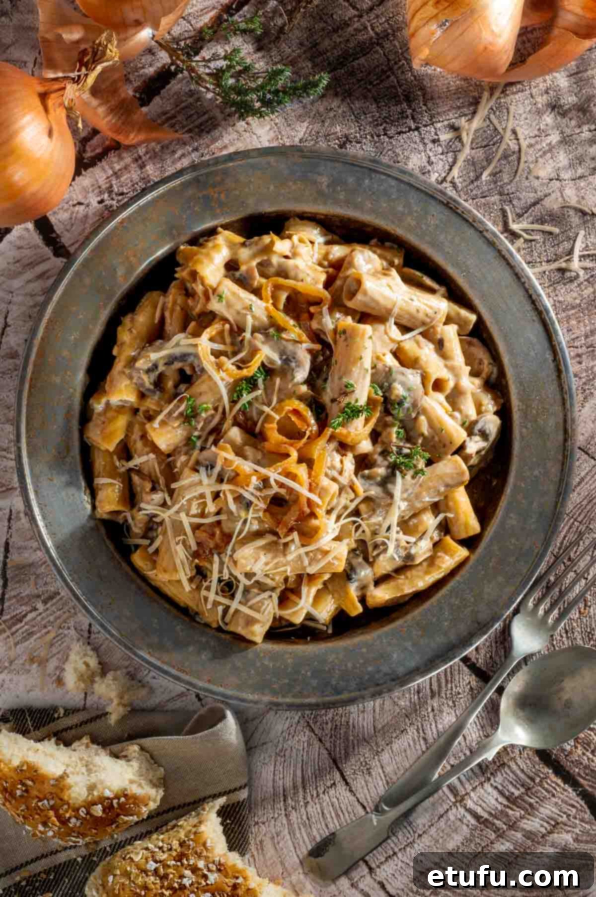 A plate of french onion pasta on a wooden background.
