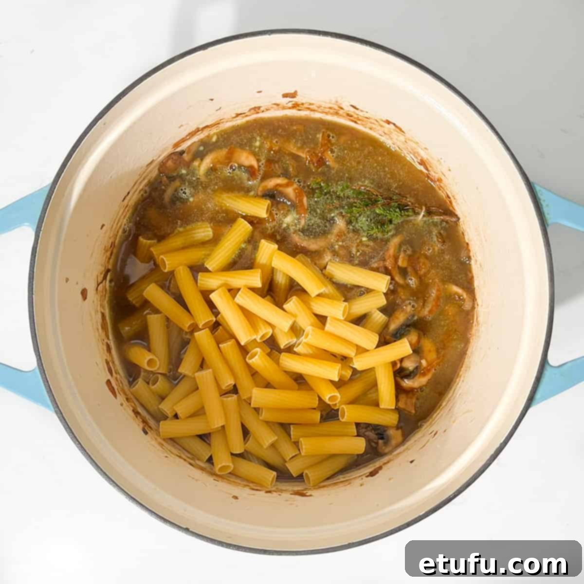 Adding the pasta and stock to the onions.
