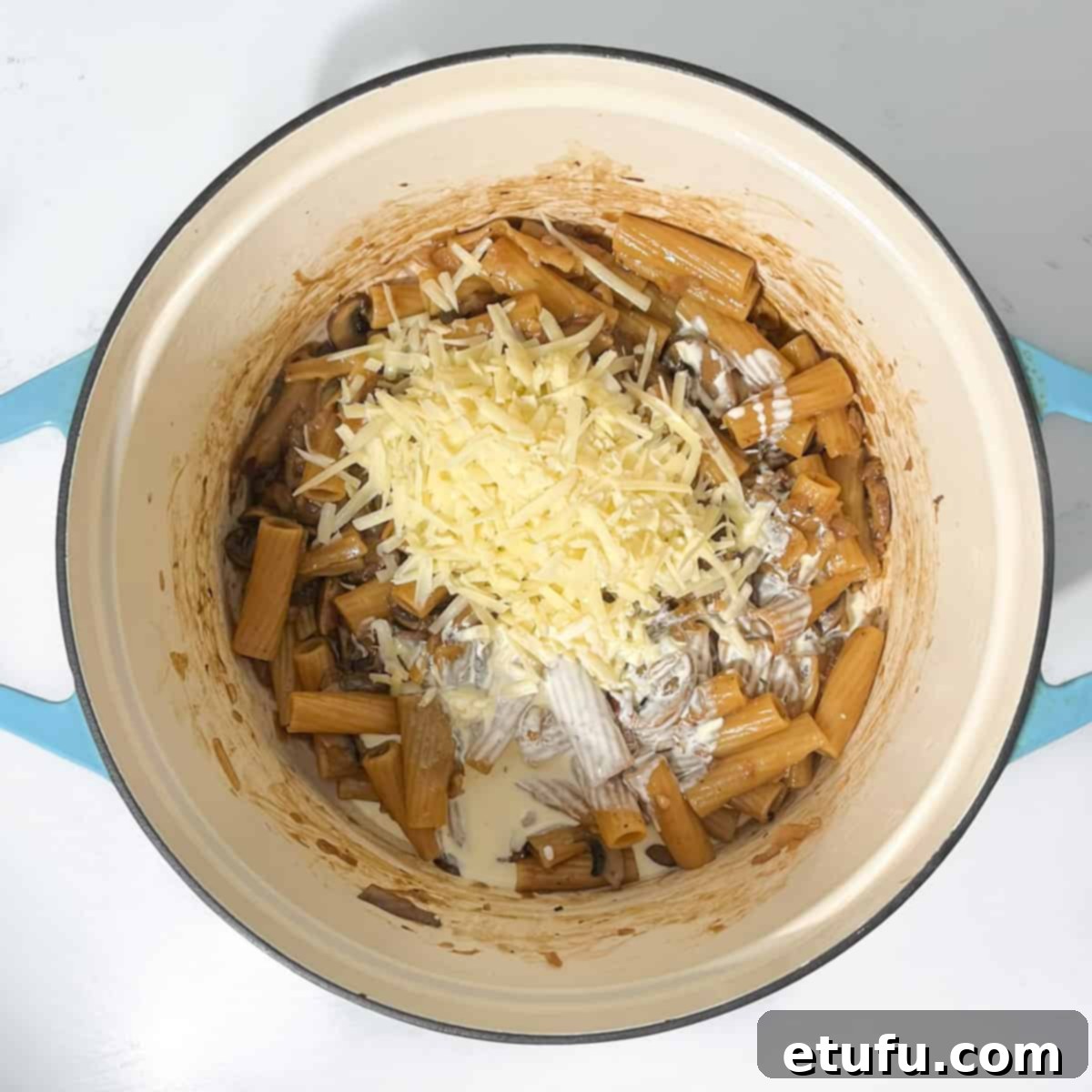 Adding cheese and cream to the french onion pasta.