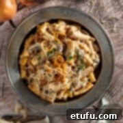 A plate of french onion pasta on a wooden background.