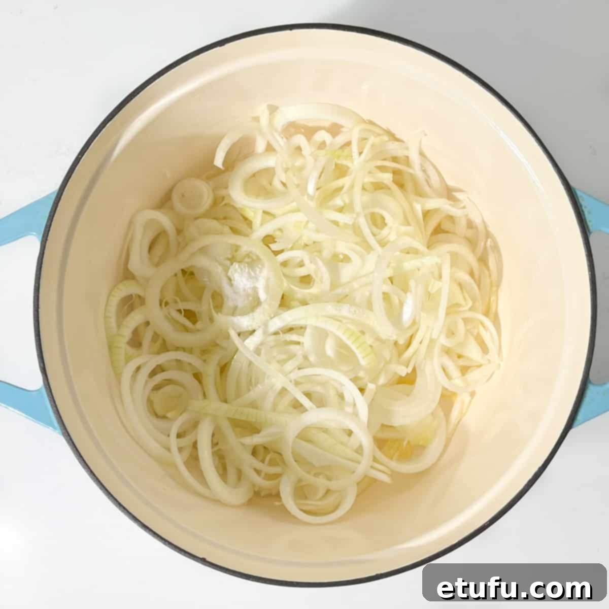 Onions frying in butter in a large cast iron pot.