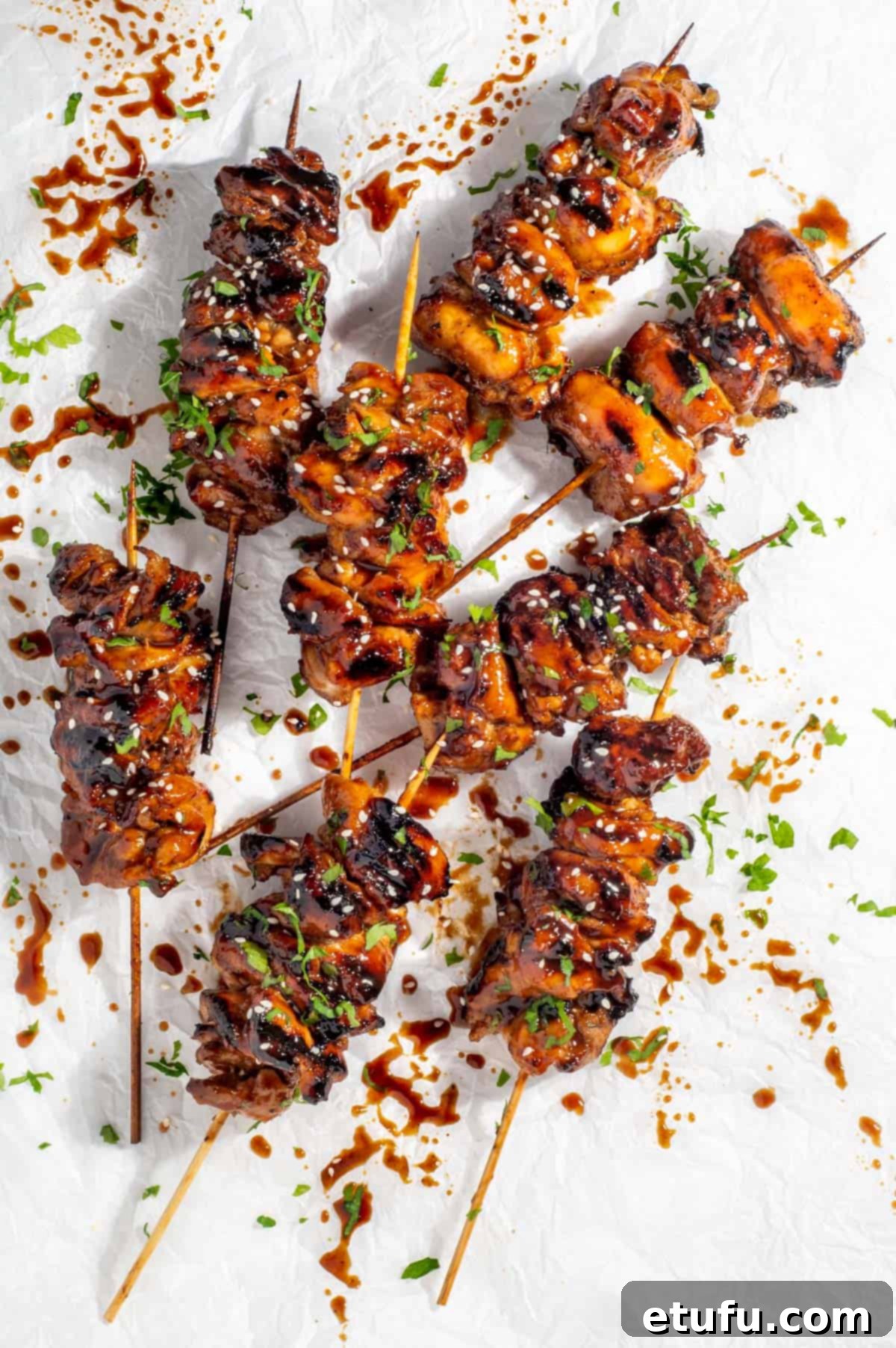Eight portions of Chinese chicken on a stick on a white background.