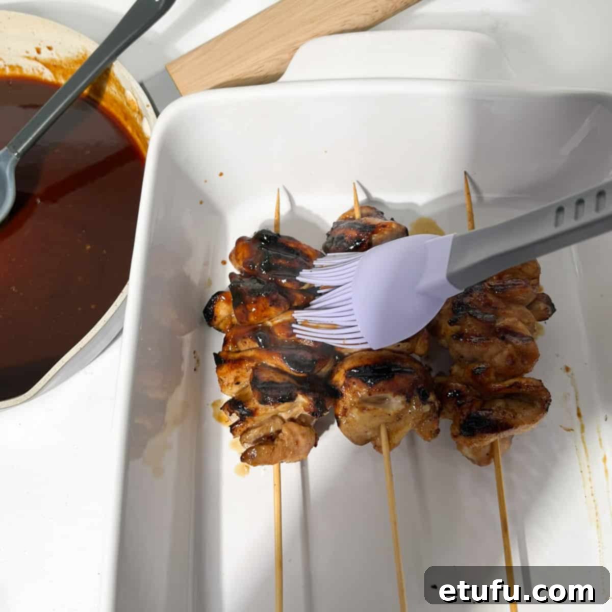 Brushing the chicken with the sauce using a pastry brush.