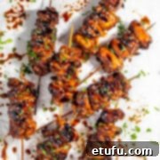 Eight portions of Chinese chicken on a stick on a white background.