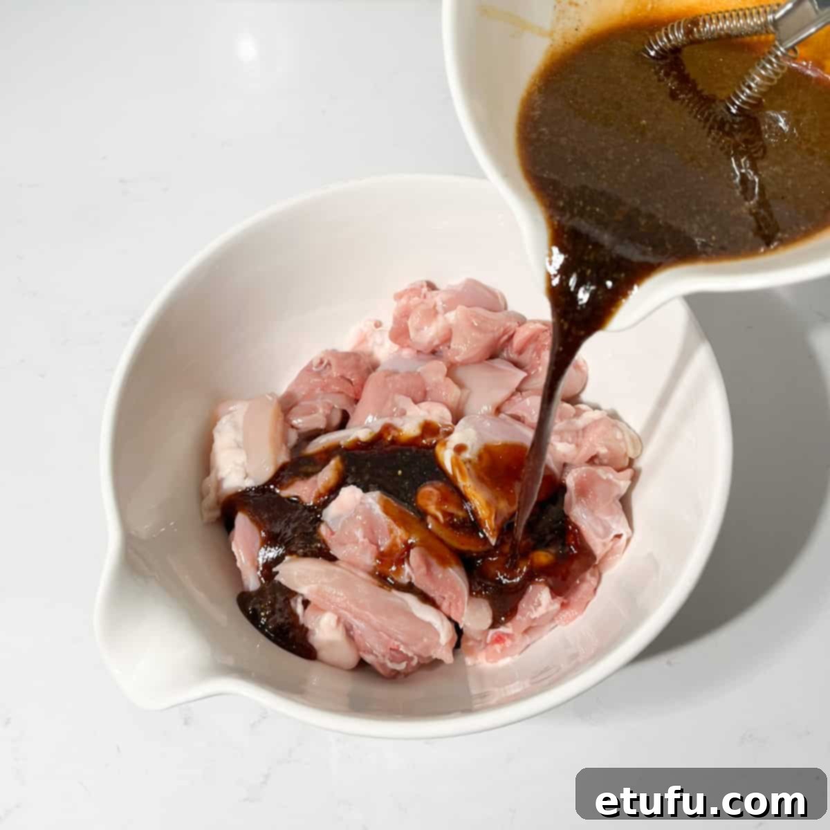 Pouring the marinade onto the chicken pieces in a large bowl.
