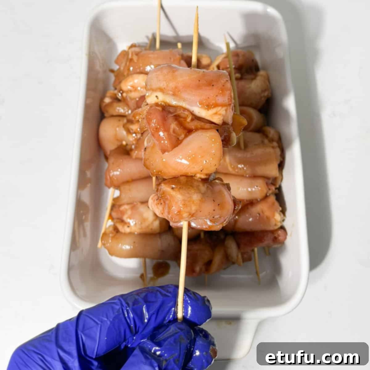 Skewering the chicken onto bamboo sticks.