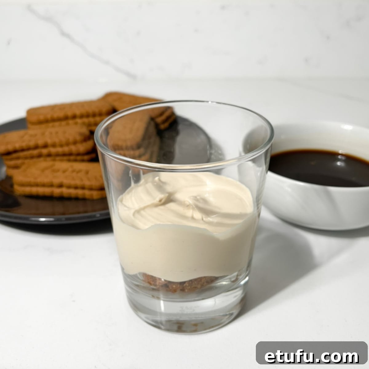 Adding the first layer of mascarpone cream on top of the biscoff cookies.