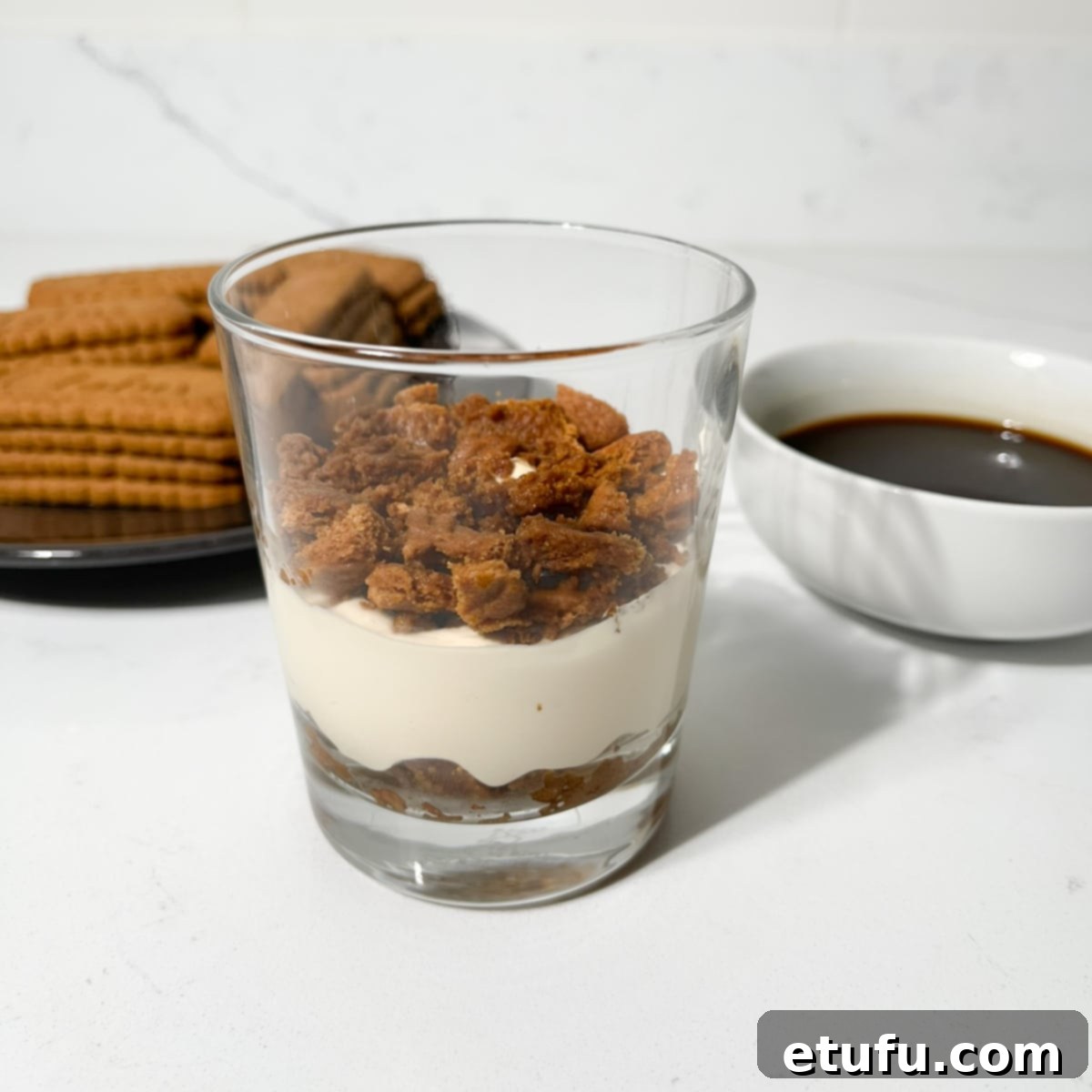 Layering cream and biscoff cookie crumbs in a glass.